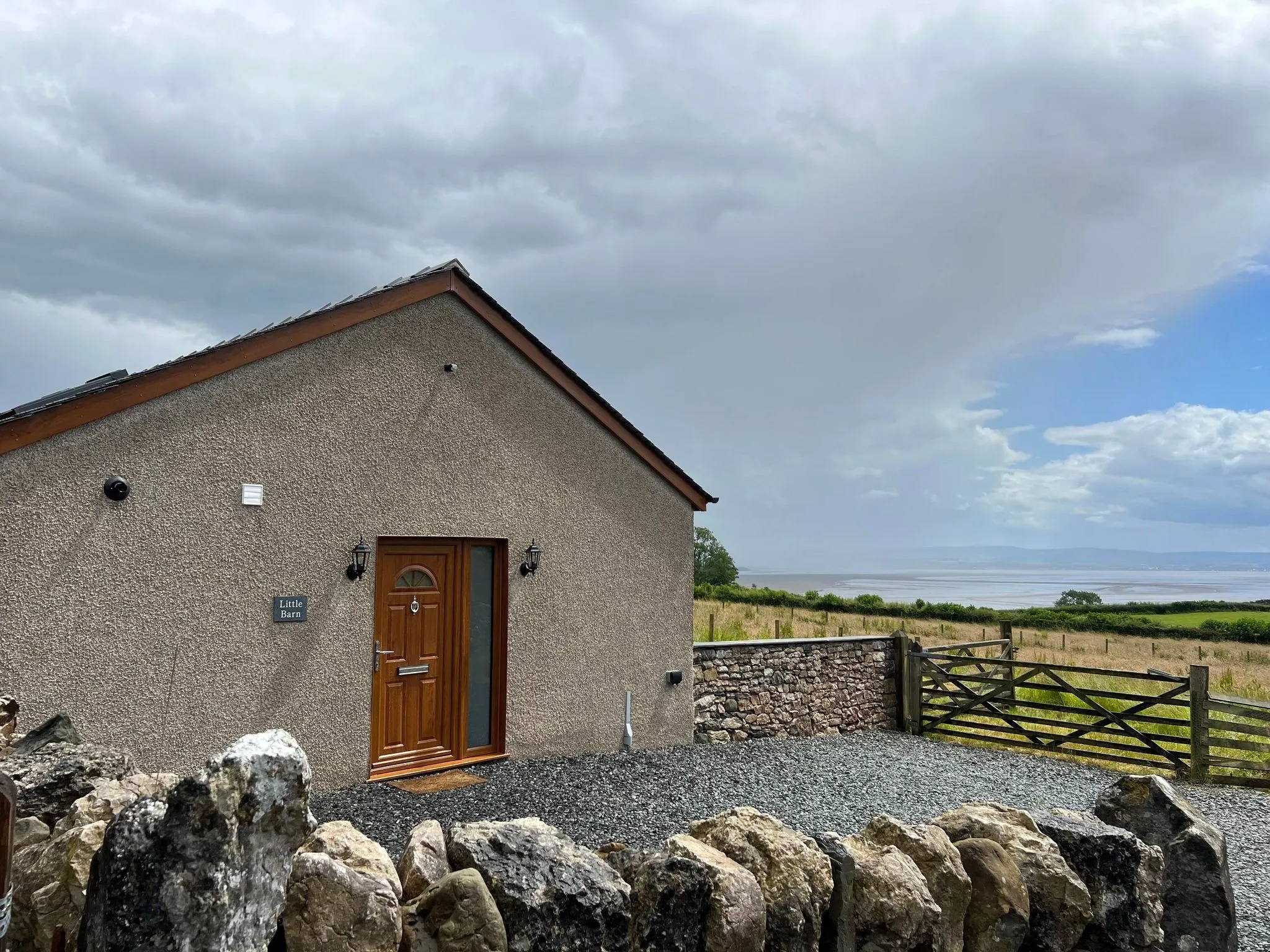 Little Barn with Morecambe Bay visible beyond its stone wall and field