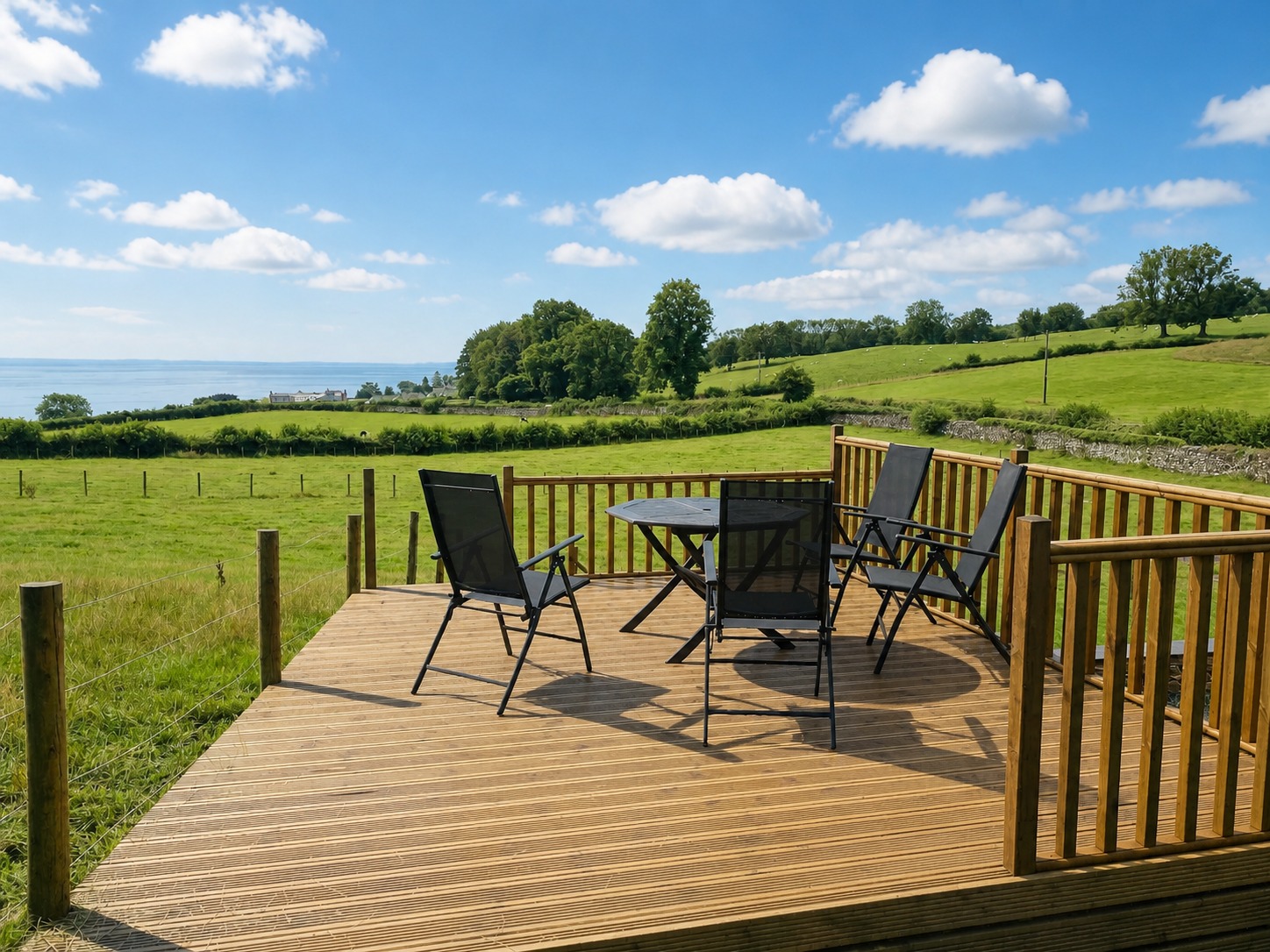 The sunlit deck at Little Barn looking across green fields towards Morecambe Bay